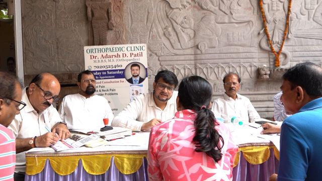 Dr. Adarsh Patil seated at the consultation table, speaking with an attendee during the check-up camp