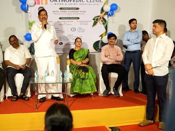 Wider view of the stage during the address, with invited guests seated on either side and attendees watching
