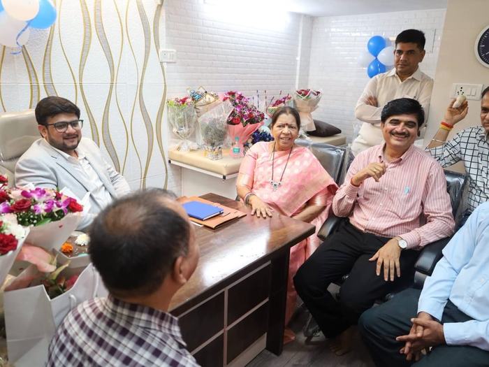 Family members and guests seated together in the consulting room, with bouquets and balloons around them