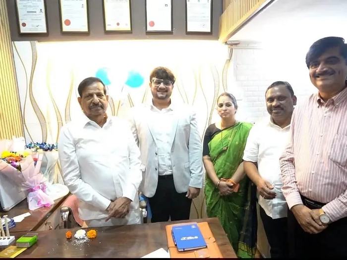 Dr. Adarsh Patil standing with Mrs. Sujata Patil, Mayor of Navi Mumbai, and Mr. Dashrath Bhagat, Deputy Mayor of Navi Mumbai, along with other guests in the consulting room, with framed certificates on the wall behind