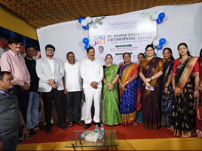 Group photograph of invited guests, family members and neighbours standing together in front of the inauguration banner